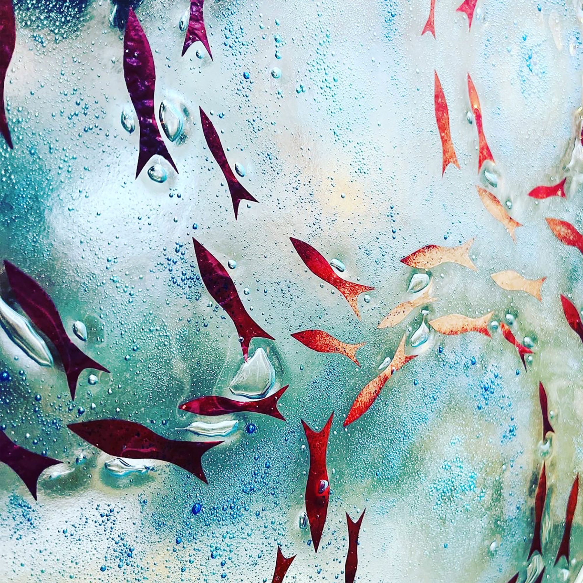a shoal of hand cut copper fish fused into recycled greenhouse glass